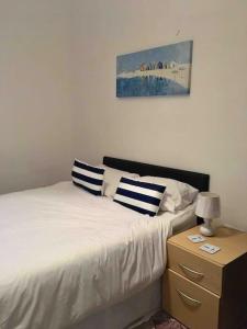a bedroom with a bed with two pillows and a night stand at Hillcrest Cottage, comfy flat, trendy Uplands area in Swansea