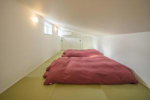 a bedroom with a red comforter on the floor at KeiU-Yakushima Luxury Guest House in Yakushima