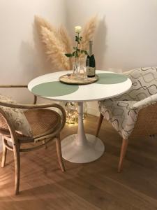 una mesa y dos sillas con un jarrón y una botella de vino en Chambre Cosy Chic, en Challans