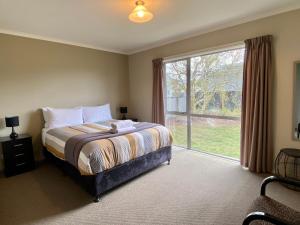 a bedroom with a bed and a large window at Rocking it On Rhoboro in Twizel