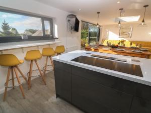 a kitchen with a large sink and yellow bar stools at Craybourne in Falmouth