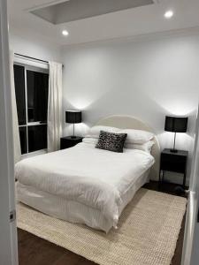a white bedroom with a large bed with two lamps at Sunnyside Luxurious 4BR Art Villa, Fireplace, Village 2mins in Wentworth Falls