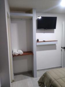 a bedroom with a tv on the wall and a bed at APARTAMENTOS AMBASSADOR in Tijuana