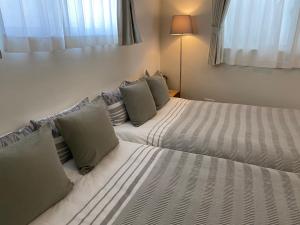 a bedroom with two beds with pillows at ホテルトーマス牧志 in Naha