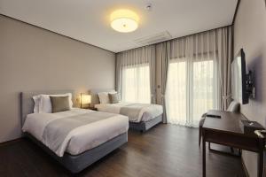 a hotel room with two beds and a desk at Camphortree Hotel and Resort in Jeju