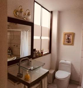 een badkamer met een toilet, een wastafel en een spiegel bij Departamento para Turistas - Aeropuerto 20Min in Lima