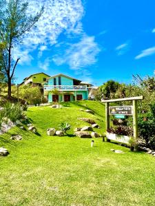 a house with a sign in front of a yard at Bella Vista Kitnets in Farol de Santa Marta