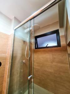 um chuveiro com uma porta de vidro e uma janela em Apartamento pé na areia - Praia do Forte em Cabo Frio