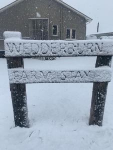 um banco coberto de neve em frente a uma casa em Wedderburn Farm Stay em Wedderburn
