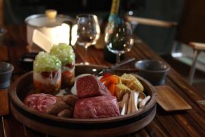 山中湖村にあるTHE DAY POST GENERAL GLAMPING VILLAGE Yamanakakoのワイングラスと一緒にテーブルの上に肉と野菜を盛り付けます