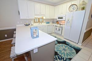 a kitchen with white cabinets and a white refrigerator at Dolphin Harbor 3C in Orange Beach