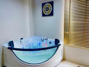 Si Maha Phot的住宿－The Desiign Hotel - SHA，浴室里设有一个大浴缸,墙上有时钟