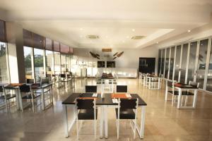 un restaurante con mesas, sillas y ventanas en Cassowary Hotel, en Runai