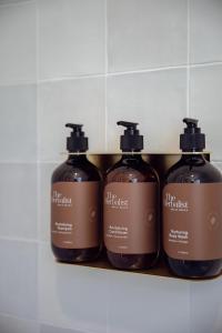 un groupe de quatre bouteilles de savon sur une étagère dans l'établissement Sunnymead Hotel, à Aireys Inlet