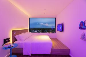 a pink bedroom with a bed and a large window at SOJO Hotel Hau Giang in Vị Thanh