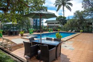 a table with an umbrella next to a swimming pool at Bird Of Paradise Hotel in Goroka