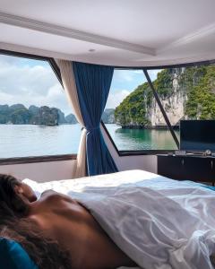 a man laying in bed on a boat at Le Theatre Cruises - Wonder on Lan Ha Bay in Ha Long