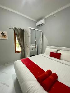 een slaapkamer met een groot wit bed met rode accenten bij AW Lor House - Yogyakarta in Sleman