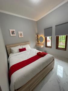 um quarto com uma cama grande com lençóis brancos e vermelhos em AW Lor House - Yogyakarta em Sleman