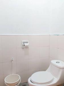 ein Badezimmer mit einem weißen WC und einem Toilettenpapier-Spender in der Unterkunft 3 Sisters Guest House 1 in Moalboal