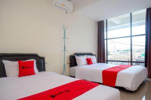 a bedroom with two beds with red and white sheets at RedDoorz near Malioboro Mall 2 in Yogyakarta