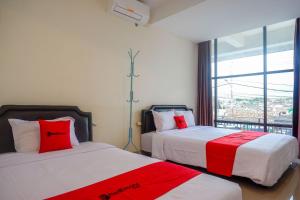 a bedroom with two beds with red and white sheets at RedDoorz near Malioboro Mall 2 in Yogyakarta