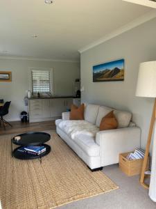 un soggiorno con divano bianco e tavolo di Foehn Cottage a Twizel