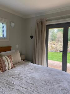 1 dormitorio con 1 cama y puerta corredera de cristal en Foehn Cottage en Twizel