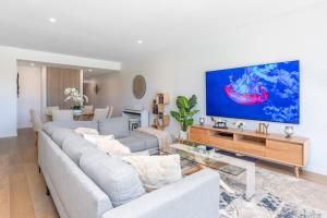 a living room with a couch and a tv on a wall at Maraboo Island Beachfront Villa in Fremantle