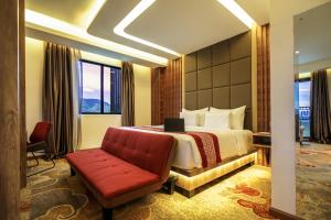 a hotel room with a bed and a red couch at Parkside Gayo Petro Hotel Takengon in Takengon