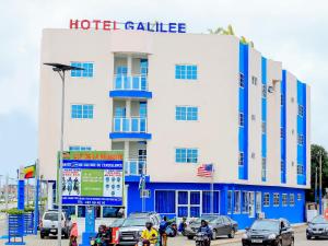 een hotelgebouw met auto's die ervoor geparkeerd staan bij Hotel Galilée in Cotonou
