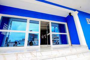 Habitación con paredes azules y ventana. en Hotel Galilée, en Cotonou