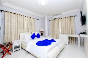 1 dormitorio blanco con 1 cama grande con almohadas azules en Hotel Galilée, en Cotonou