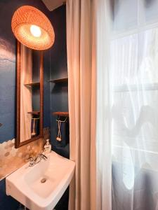 a bathroom with a sink and a mirror and a window at ITH Mission Beach Backpacker Hostel in San Diego