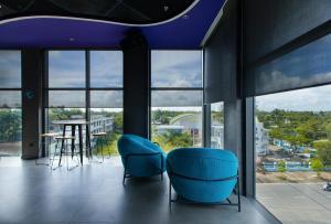 twee blauwe stoelen in een kamer met ramen bij SOJO Hotel Hau Giang in Vị Thanh