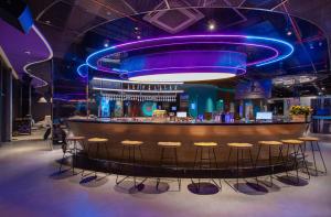 un bar en una discoteca con iluminación púrpura y taburetes en SOJO Hotel Hau Giang en Vị Thanh