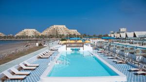 a swimming pool with lounge chairs and a beach at Banan Beach in Ras al Khaimah