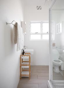 a white bathroom with a sink and a toilet at Shabby Chic in Muizenberg