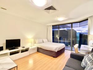 a bedroom with a bed and a tv and a couch at Milson Serviced Apartments in Sydney