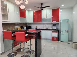 une cuisine avec des placards rouges et des tabourets de bar rouges dans l'établissement Desaru Brown House Pool-Table Tennis-KTV-BBQ-Netflix-Home Theatre, à Kota Tinggi