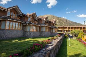 a house with a stone wall and flowers in the yard at Casa Andina Premium Valle Sagrado Hotel & Villas in Urubamba