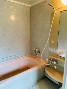 a bath tub with a hose in a bathroom at 民泊JOYFUL天然温泉付きログハウス in Shiraoi