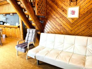 a living room with a white couch and a chair at 民泊JOYFUL天然温泉付きログハウス in Shiraoi