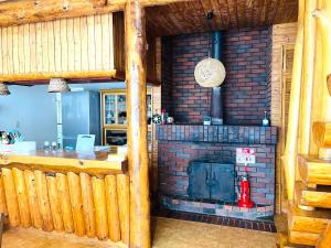 a kitchen with a brick fireplace in a room at 民泊JOYFUL天然温泉付きログハウス in Shiraoi