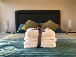 a stack of towels sitting on top of a bed at Elegante y acogedor departamento con gran vista, cercano a todo in Concepción