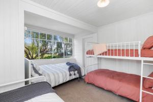 a bedroom with two bunk beds and a window at Karitane Cottage - Karitane Holiday Home in Karitane