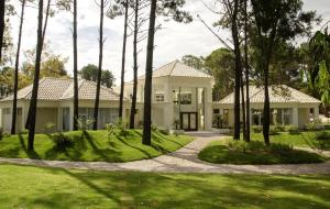 une grande maison blanche avec des arbres devant elle dans l'établissement GREEN PARK - Apartamento Torre J - Punta del Este - Resort & Spa, à Punta del Este