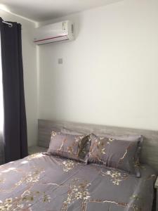 a bedroom with a bed with a gray comforter and pillows at BR COURT-PARKVIEW SODNAC in Quatre Bornes