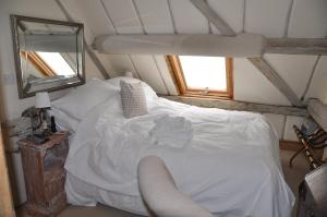 1 dormitorio con cama blanca y espejo en The Old Barn, en North Stoke