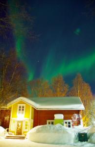 a cabin with the northern lights in the sky at LAURI Historical Log House Manor in Rovaniemi